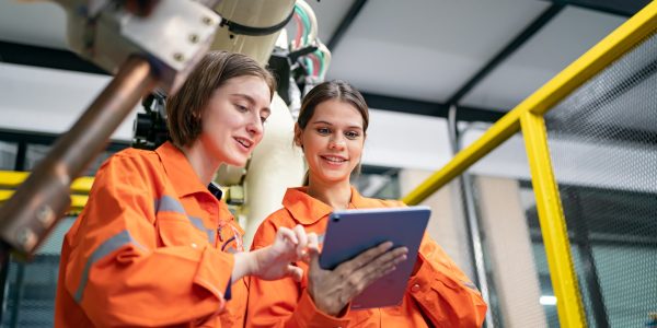 Female Engineer check and control automation robot arms machine in factory. robotics manufacturing.